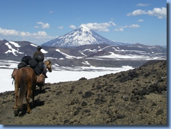 Group of riders on horseback in front of Lanin Volcanoe on a horseback trailride in chilean andes
